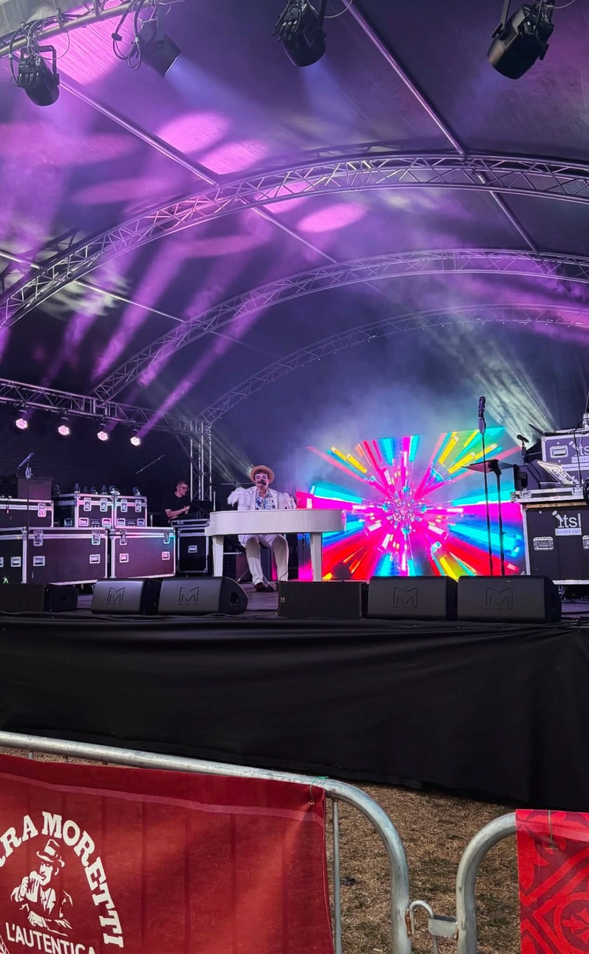 Festival main stage lit with purple beams and a large video wall