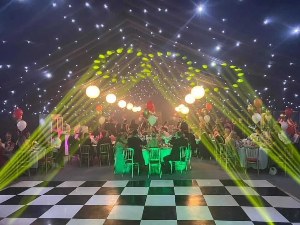 Marquee wedding lit with green beams, starcloth ceiling and festoon lighting